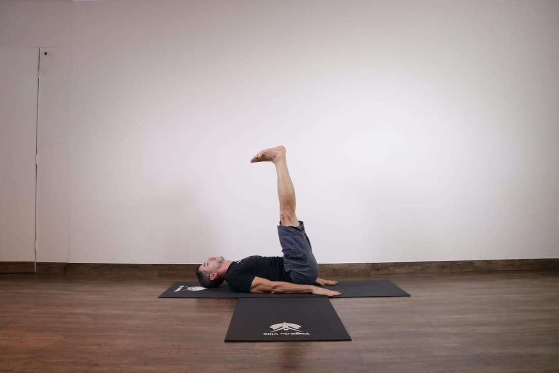 Professor Márcio demonstra a postura Ardha Halasana no estúdio Yoga du Ville, referência em yoga na Tijuca.