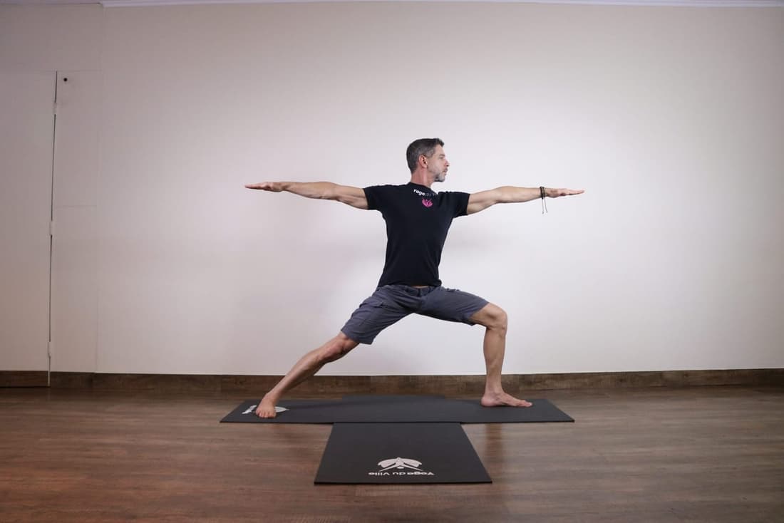Instrutor Márcio na postura Virabhadrasana II, Guerreiro 2 do yoga, em aula no estúdio Yoga du Ville, Tijuca, RJ