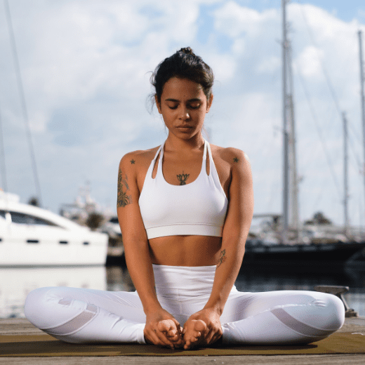 Mulher praticando Baddha Konasana, postura do trono no yoga, sentada com a sola dos pés unidas e joelhos abertos