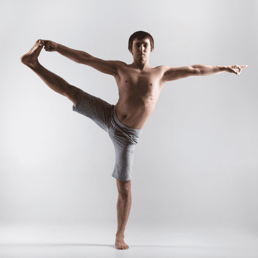 Homem praticando Utthita Hasta Padangusthasana no yoga, em equilíbrio com a perna estendida e segurando o pé com a mão