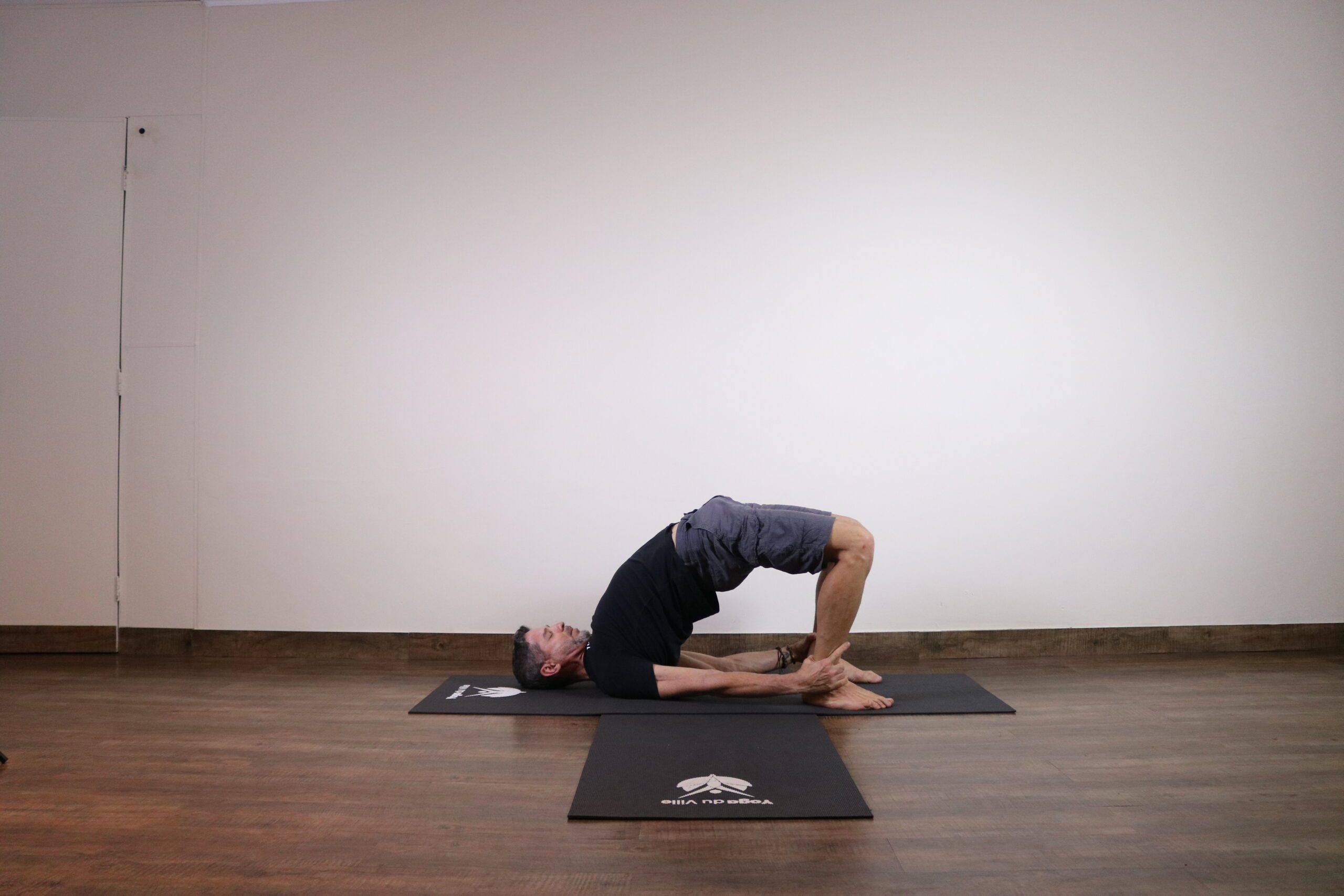 Professor Márcio na postura Setu Bandha Sarvangasana durante aula de yoga no Yoga du Ville, Tijuca – RJ.