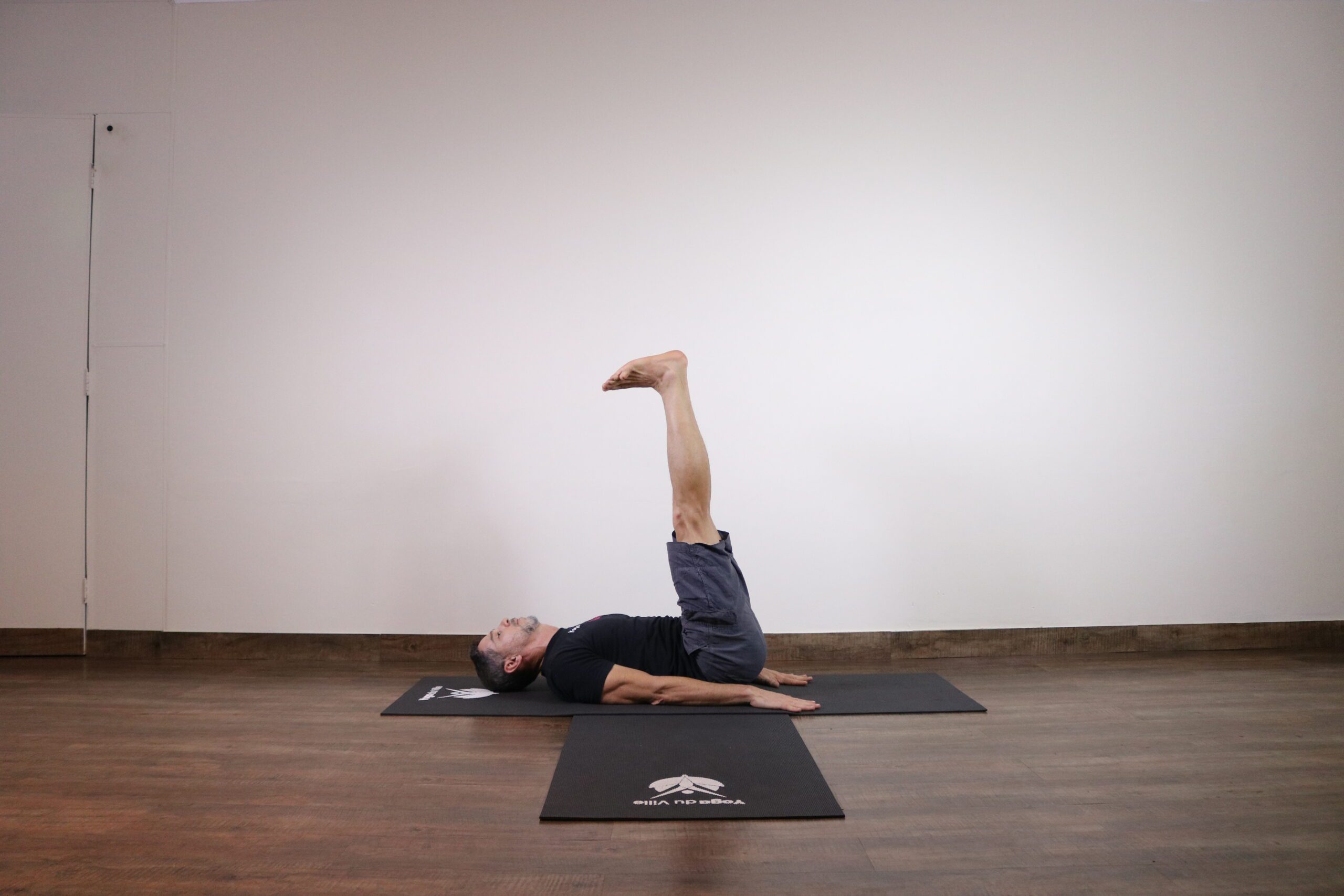 Professor Márcio demonstra a postura Ardha Halasana no estúdio Yoga du Ville, referência em yoga na Tijuca.