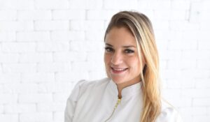 Massoterapeuta Priscila vestindo jaleco branco olhando para câmera segurando ventosas.