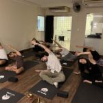 Grupo de alunos em aula de yoga no studio Yoga du Ville, localizado na Praça Saens Peña, Tijuca.